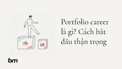Minh họa cho Portfolio career là gì? Cách bắt đầu thận trọng: Một người đứng vững trên bệ lớn tượng trưng cho công việc hiện tại, đồng thời thử đặt một chân lên bệ nhỏ kế bên tượng trưng cho vai trò mới.